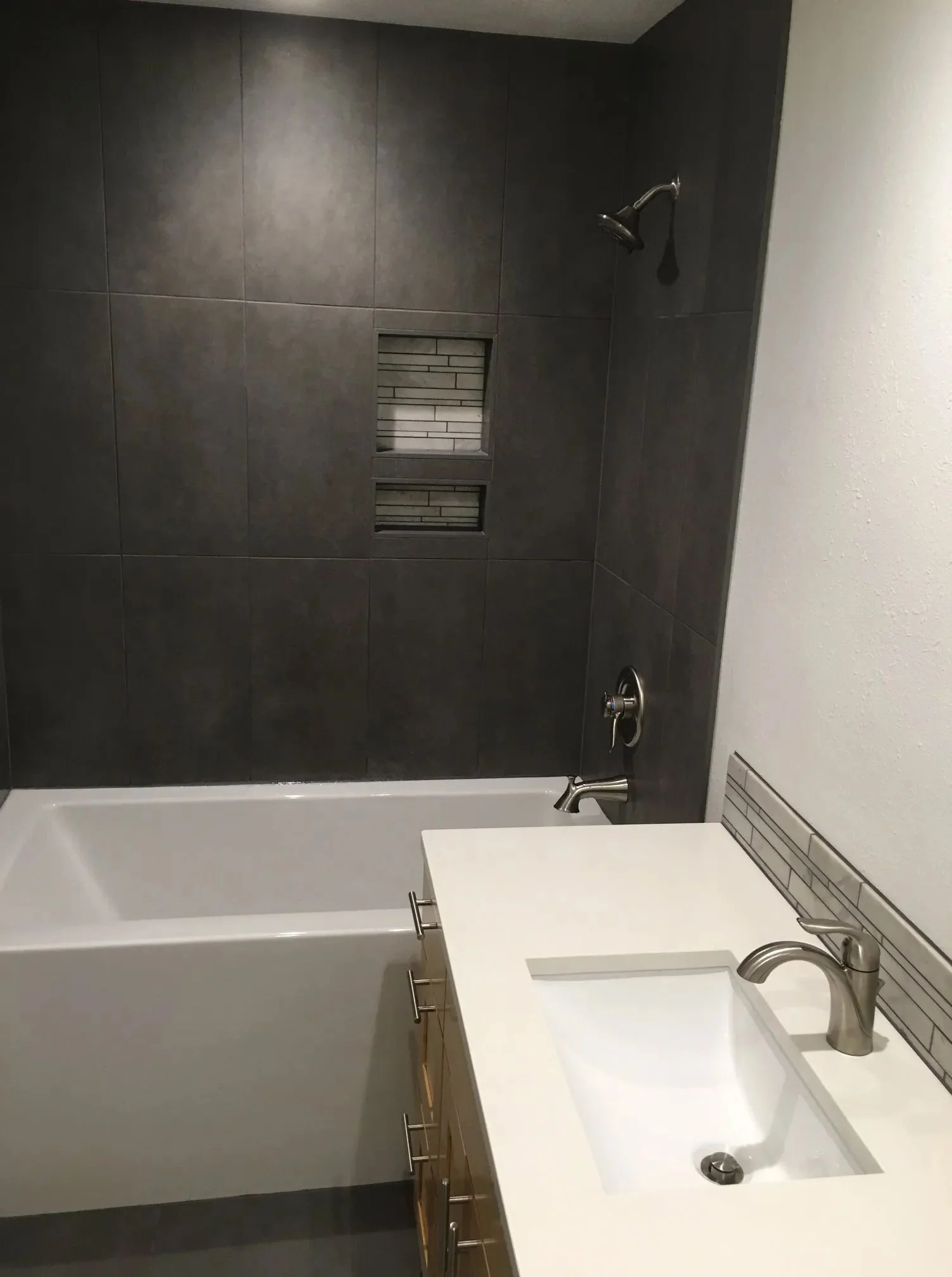 Dark large-format tile tub surround with a floating vanity