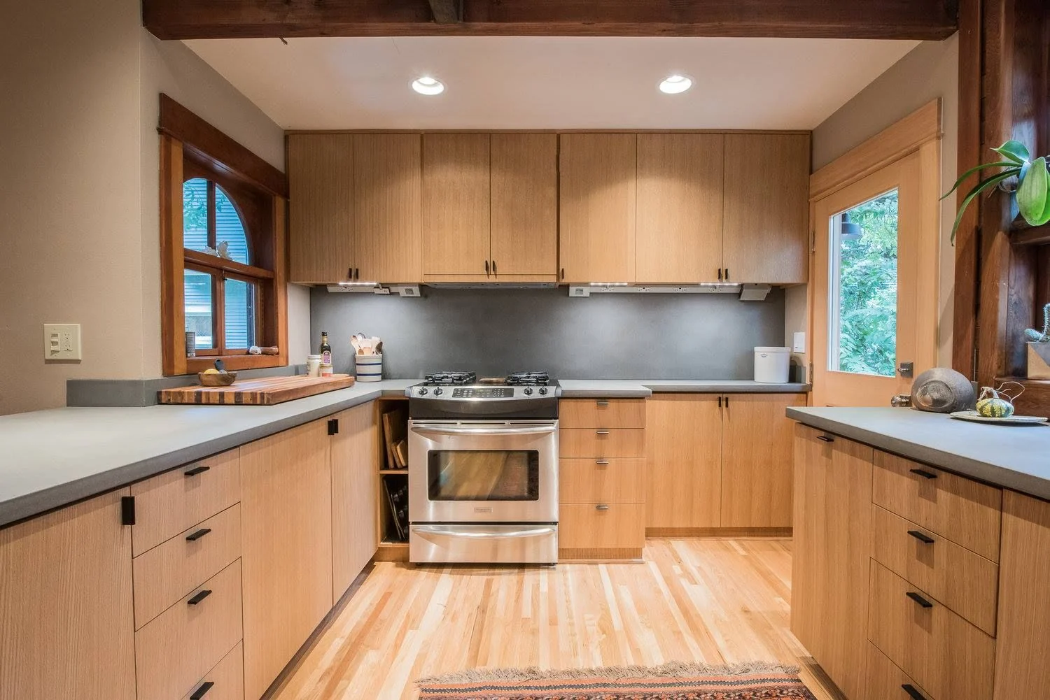 Warm wood kitchen with a stainless range and arched window