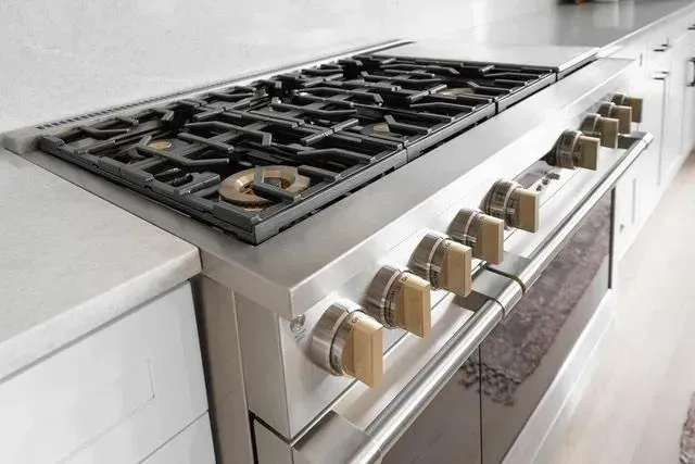 Professional range with brass knobs against quartz