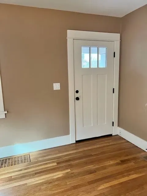 Restored white Craftsman entry door against tan walls and refinished hardwood