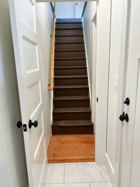 Stairs landing — original dark-stained treads and marble tile entry