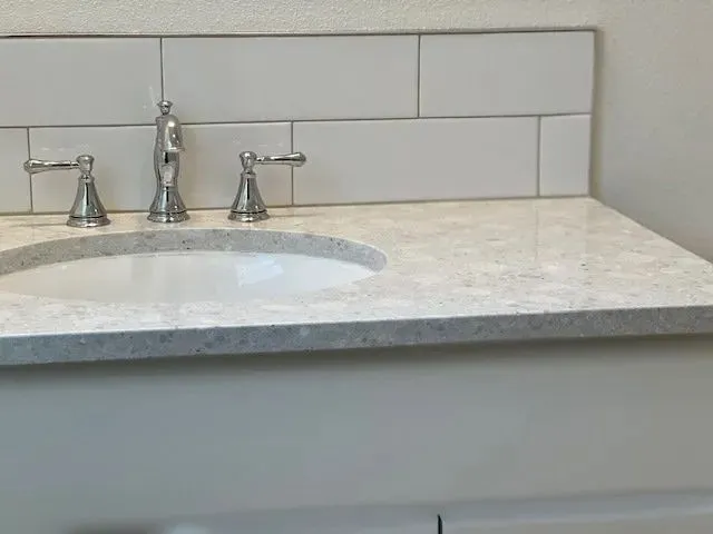 Bath sink detail with chrome two-handle faucet on marble counter