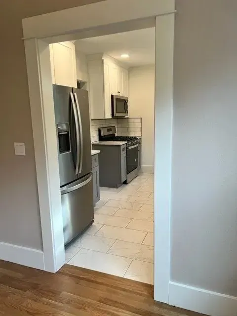 Kitchen viewed from main hall through doorway, French-door fridge and subway tile