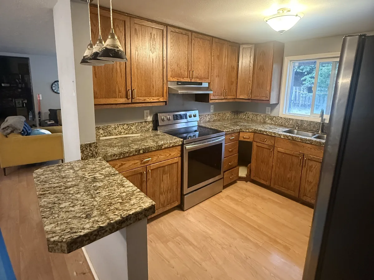 Oak cabinets, granite tile counters, and a laminate floor before the remodel