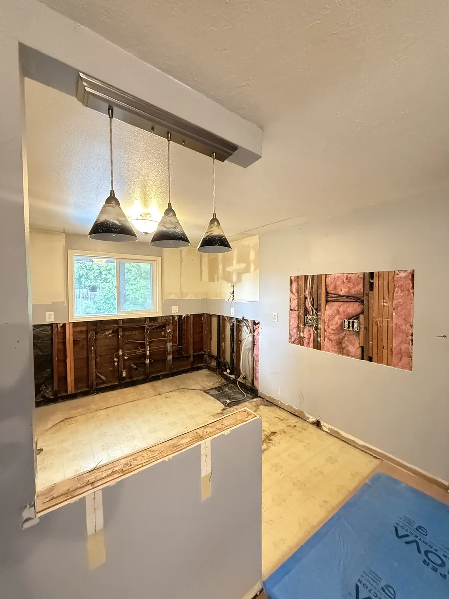Gutted kitchen with the old pendants still hanging over the peninsula framing