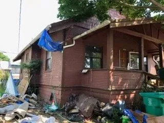 Bungalow exterior during demolition with debris and tarps