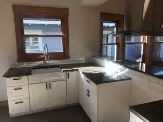 Kitchen mid-construction with white cabinets and original trim
